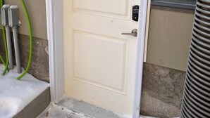 A closed door with a keypad lock, a green hose, and a vent on the right. - Cozy basement suite in Elerslie . (Edmonton)