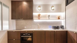 Una cocina moderna con armarios de madera, horno empotrado, fregadero y encimera con cafetera y tostadora.