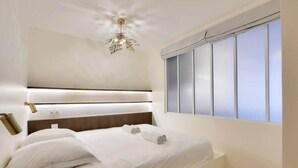 Un dormitorio moderno con una cama grande, una lámpara de techo y una ventana con persianas.