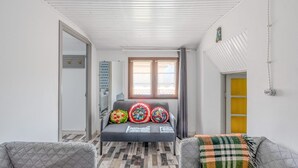 A narrow hallway with a sofa and two armchairs, a patterned floor, and a window with curtains.
