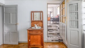 A hallway with a wooden cabinet, a mirror, and a white door.