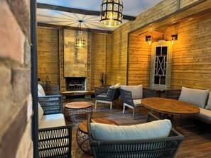 Un interior acogedor de madera con muebles de mimbre, una chimenea de piedra e iluminación colgante.