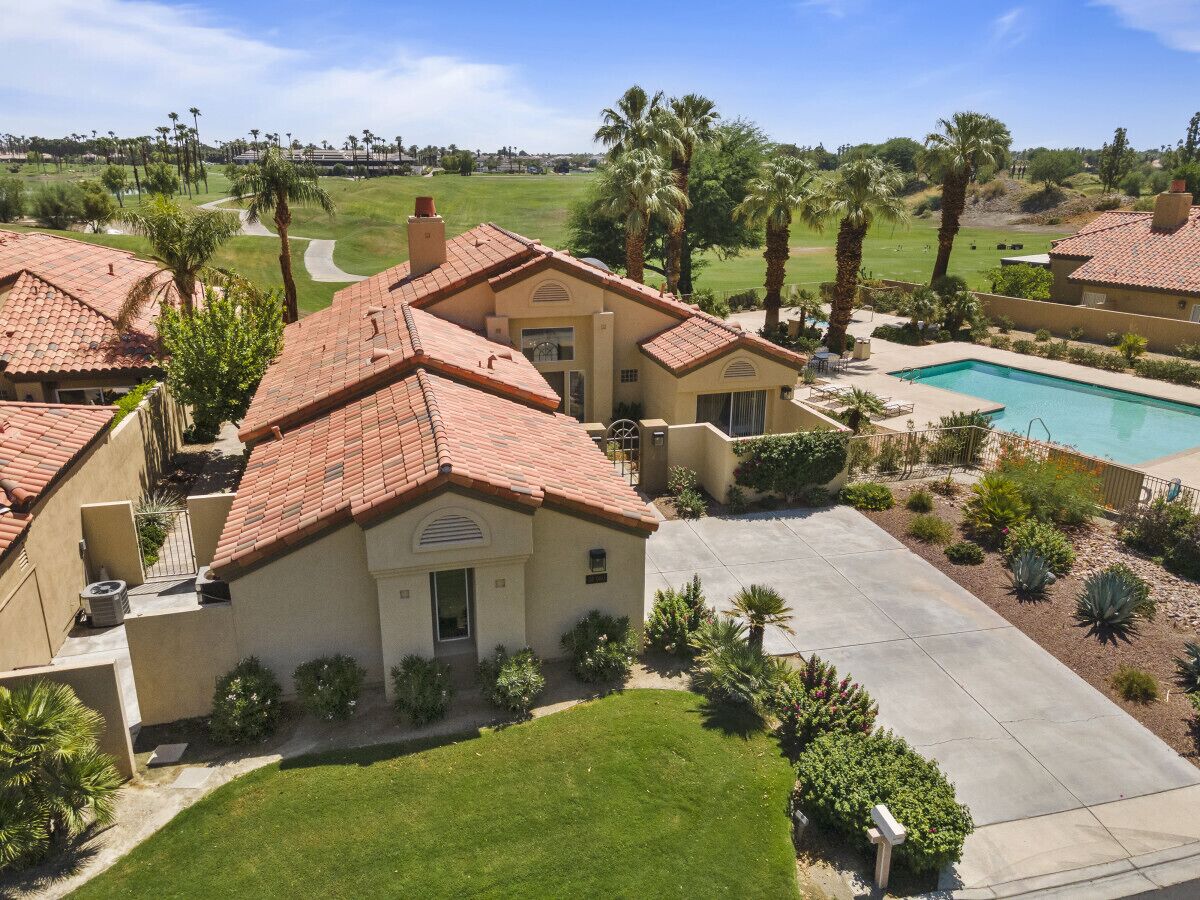 A residential property with a swimming pool, a well-maintained lawn, and a view of a golf course.