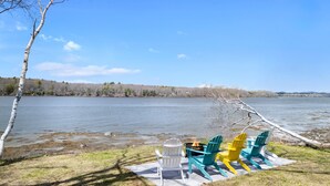 A lakeside view with a fire pit and Adirondack chairs. - Sunset Cove in Saint George Maine (Saint George)