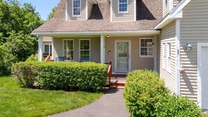 A two-story house with a covered porch, a front door, and a small front yard. - Sunset Cove in Saint George Maine (Saint George)