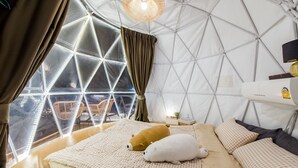 A cozy room with a bed, pillows, and a window overlooking a terrace. - Baandomedoodao Pool Villa Cha-Am (Cha-am)