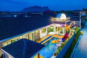 A modern hotel with a swimming pool, outdoor seating, and a view of mountains. - Baandomedoodao Pool Villa Cha-Am (Cha-am)