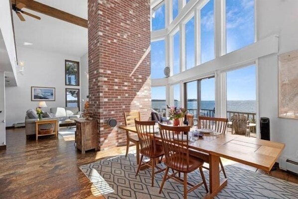 A dining area with a brick column, wooden table, and chairs, overlooking a scenic view.
