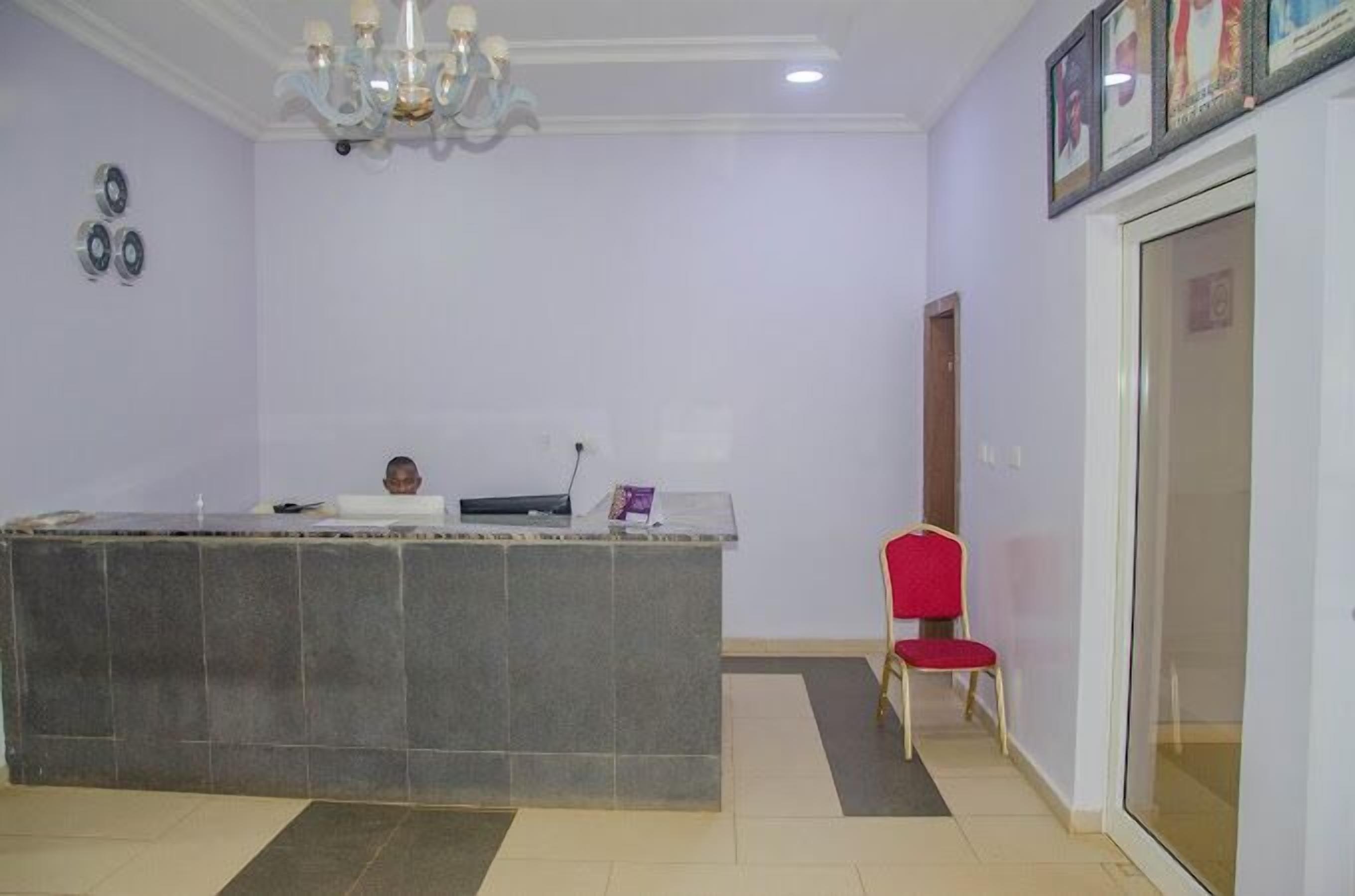 A reception area with a marble counter, a red chair, and a chandelier.