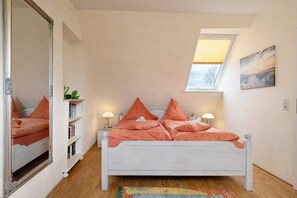 Un dormitorio con cama, tragaluz, estantería y un cuadro en la pared.
