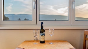 A bottle of wine and two glasses on a table by a window with a view of the sea. - 'Room 1' with Shared Garden and Wi-Fi (Reichenau)