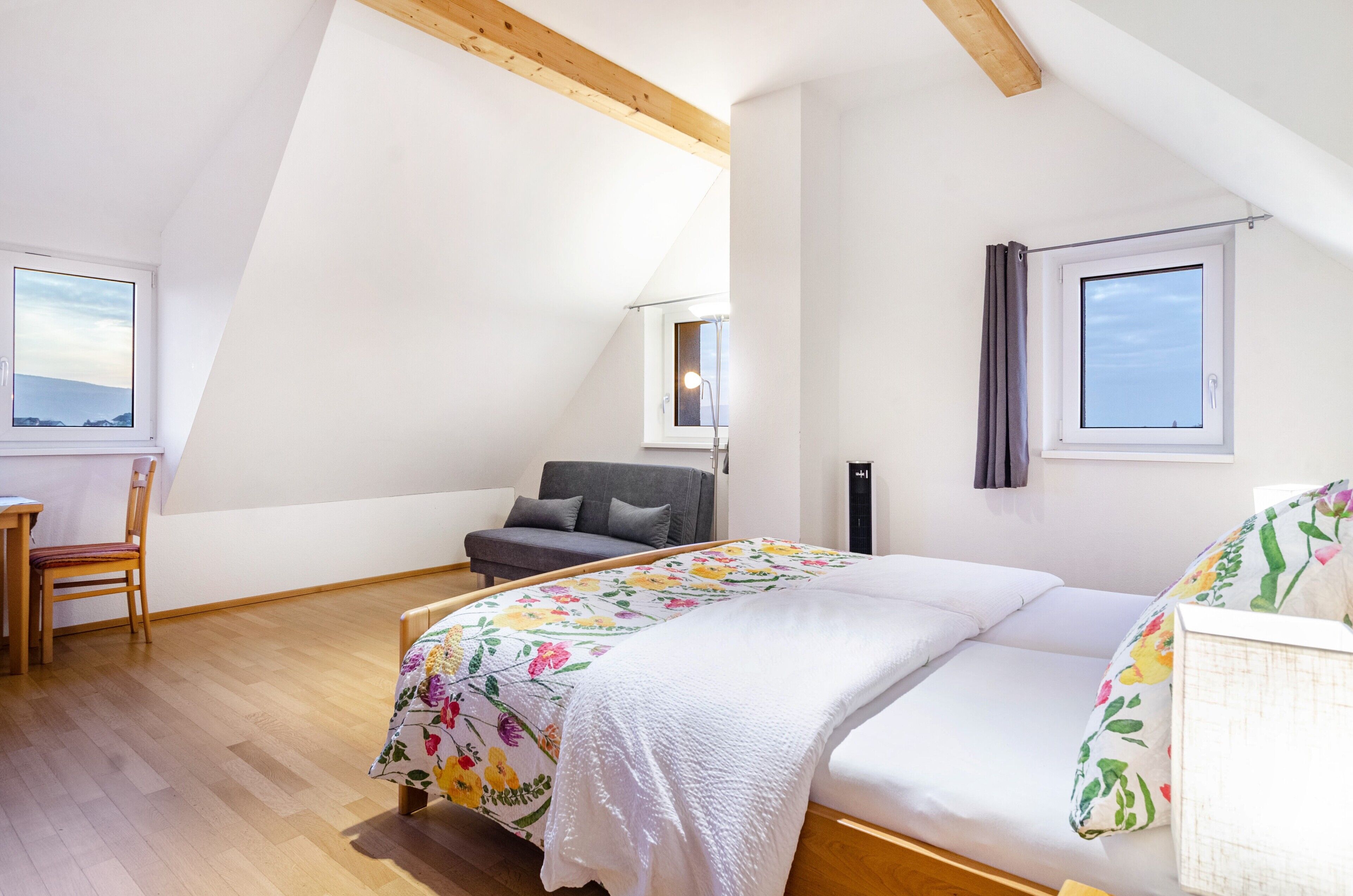 Un dormitorio con cama, escritorio, silla y ventana.
