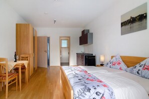 Une chambre à coucher comprenant un lit, un bureau, une chaise, une armoire et donnant sur une rivière.