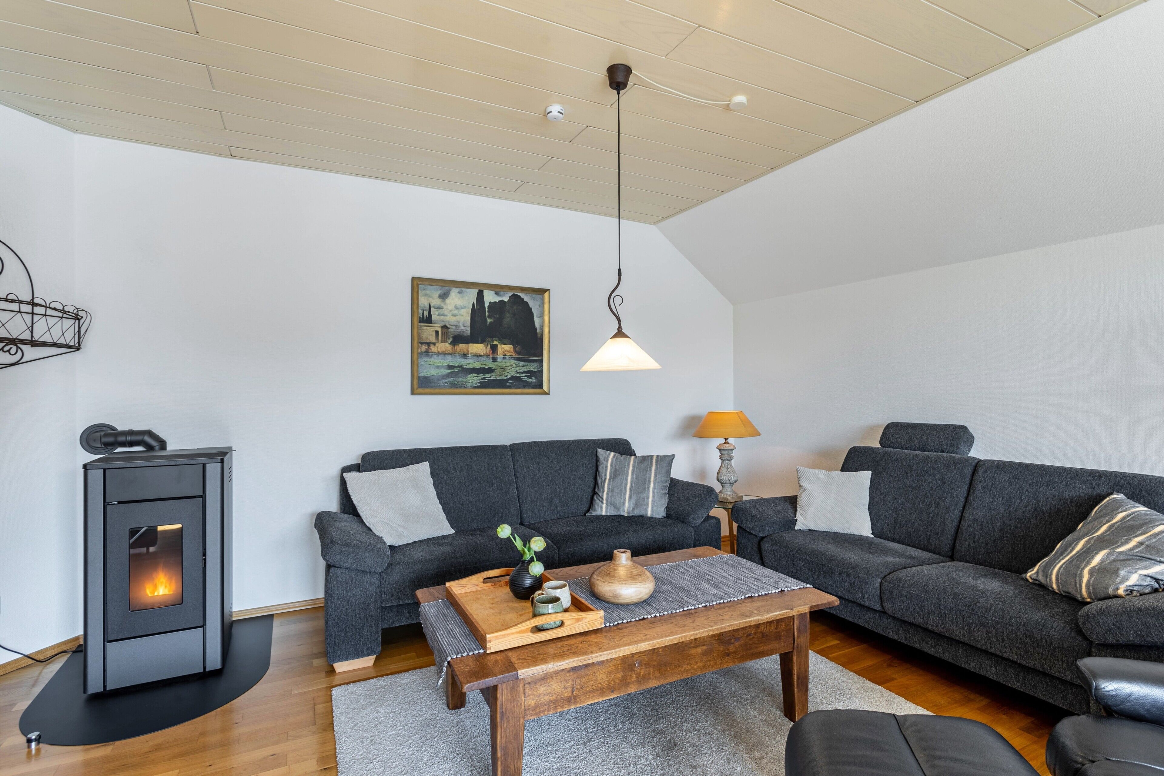 A living room with a sofa, a wooden coffee table, a fireplace, and a painting on the wall.