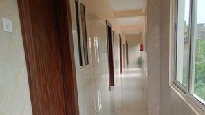 Un pasillo con puertas de madera y suelo de mármol que conduce a una habitación con ventana.
