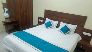 Una cama bien hecha con colcha azul y blanca, dos almohadas y un cabecero de madera.