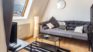 Un salon moderne avec un canapé, une table basse, un téléviseur et une fenêtre donnant sur un beau paysage.