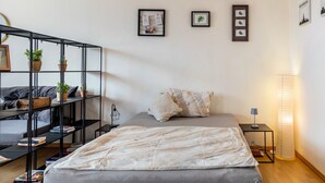 Une chambre à coucher comprenant un lit, une table de chevet, une lampe, une bibliothèque et des œuvres d’art murales.