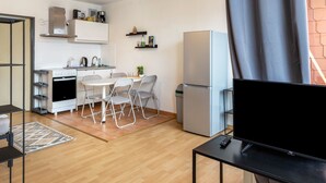 Une cuisine compacte comprenant un coin repas, un réfrigérateur et un téléviseur posé sur un meuble.