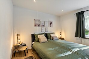 A bedroom with a bed, bedside tables, a lamp, and wall art.