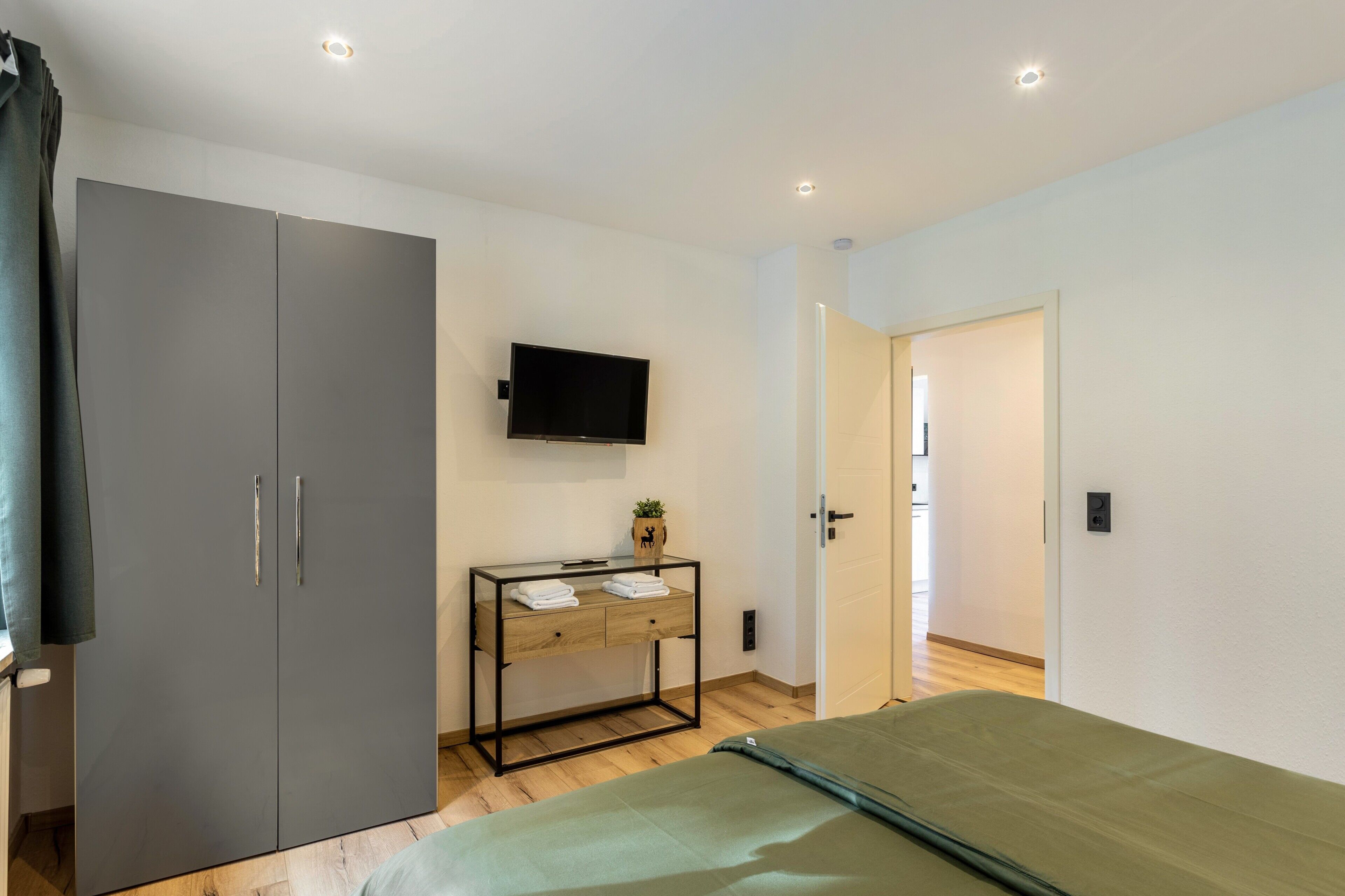 Una camera da letto con un letto, un armadio, un comodino, una TV e una porta che dà su un'altra stanza.
