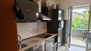 Une cuisine moderne dotée d’un évier en acier inoxydable, d’un plan de travail en bois et d’appareils électroménagers encastrés.
