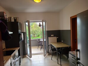 Une cuisine moderne avec un coin repas, une vue sur le jardin et une porte-fenêtre coulissante donnant sur un balcon.