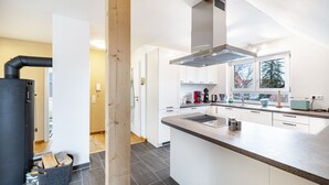 Una cocina moderna con armarios blancos, una isla central y una estufa con campana.