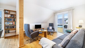 Amplia sala de estar con una gran estantería, un sofá cómodo, un televisor y un balcón con vistas.