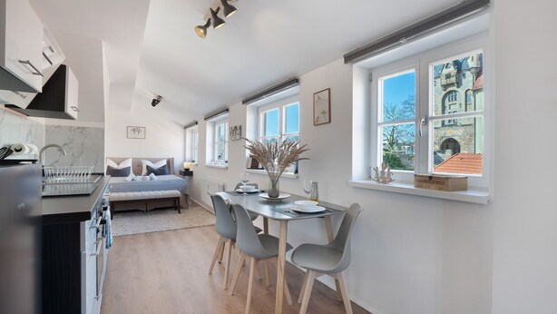 A modern kitchen with a dining area, large windows, and a view of a historic building. - Apartment 'Domblick Deluxe' with Wi-Fi (Meißen)