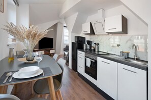 A modern kitchen with white cabinets, a black countertop, and a dining area with a table set for two.