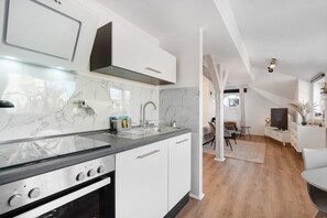 A modern kitchen with white cabinets, a stainless steel stove, and a marble backsplash.