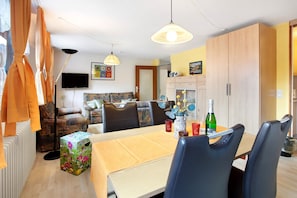 Un comedor con una mesa, sillas, un televisor y un mueble.