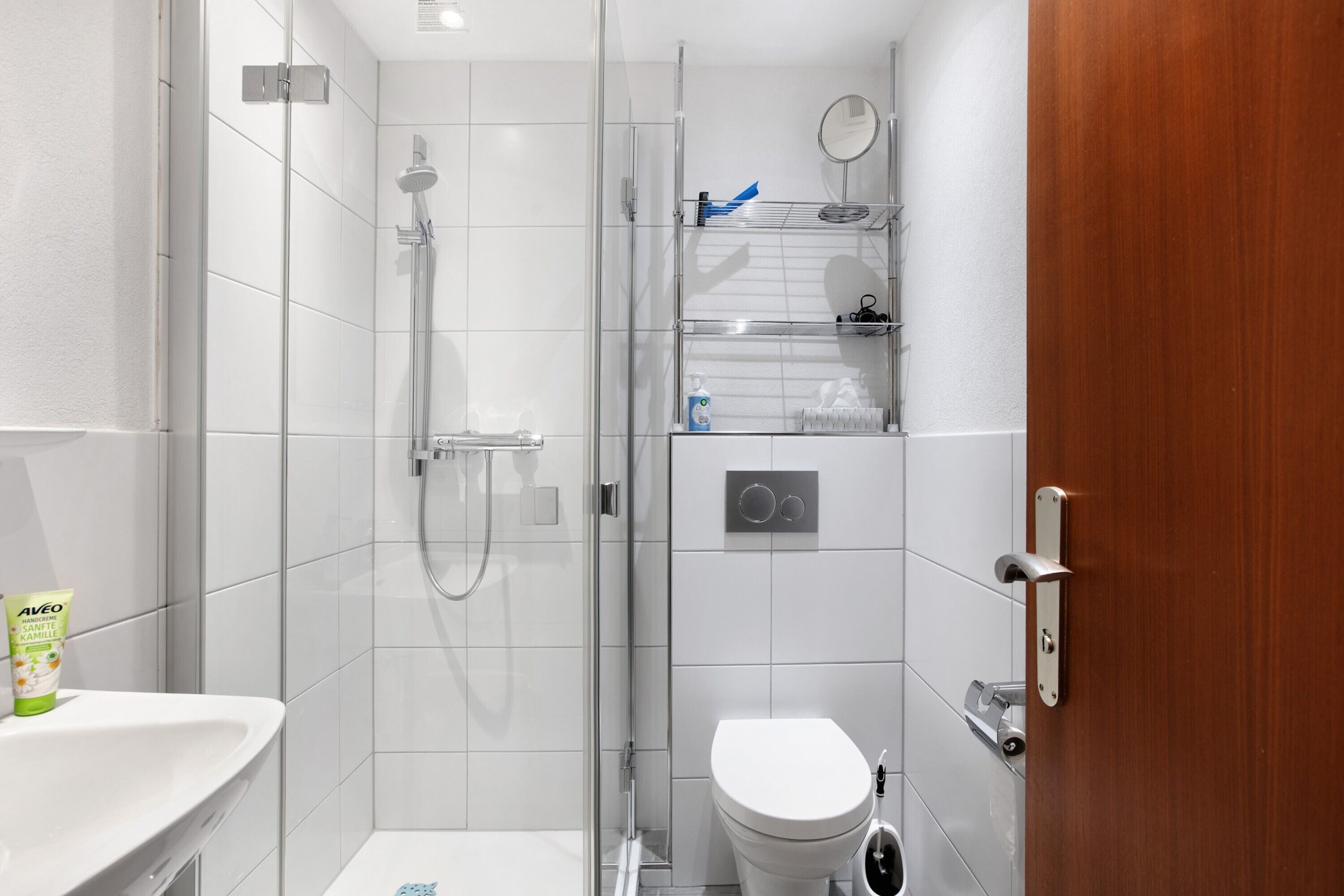 Ein modernes Badezimmer mit Duschkabine aus Glas, Toilette und Waschbecken.