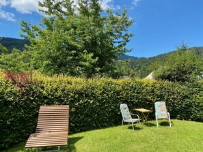Een tuin met een houten bank, twee stoelen en een kleine tafel.