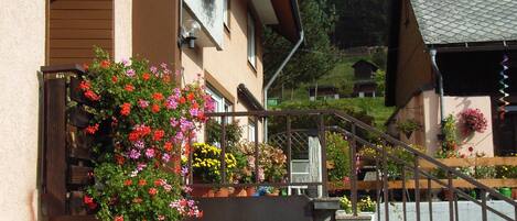 Un edificio con una escalera que lleva a una plataforma, rodeado de jardineras y plantas en macetas.