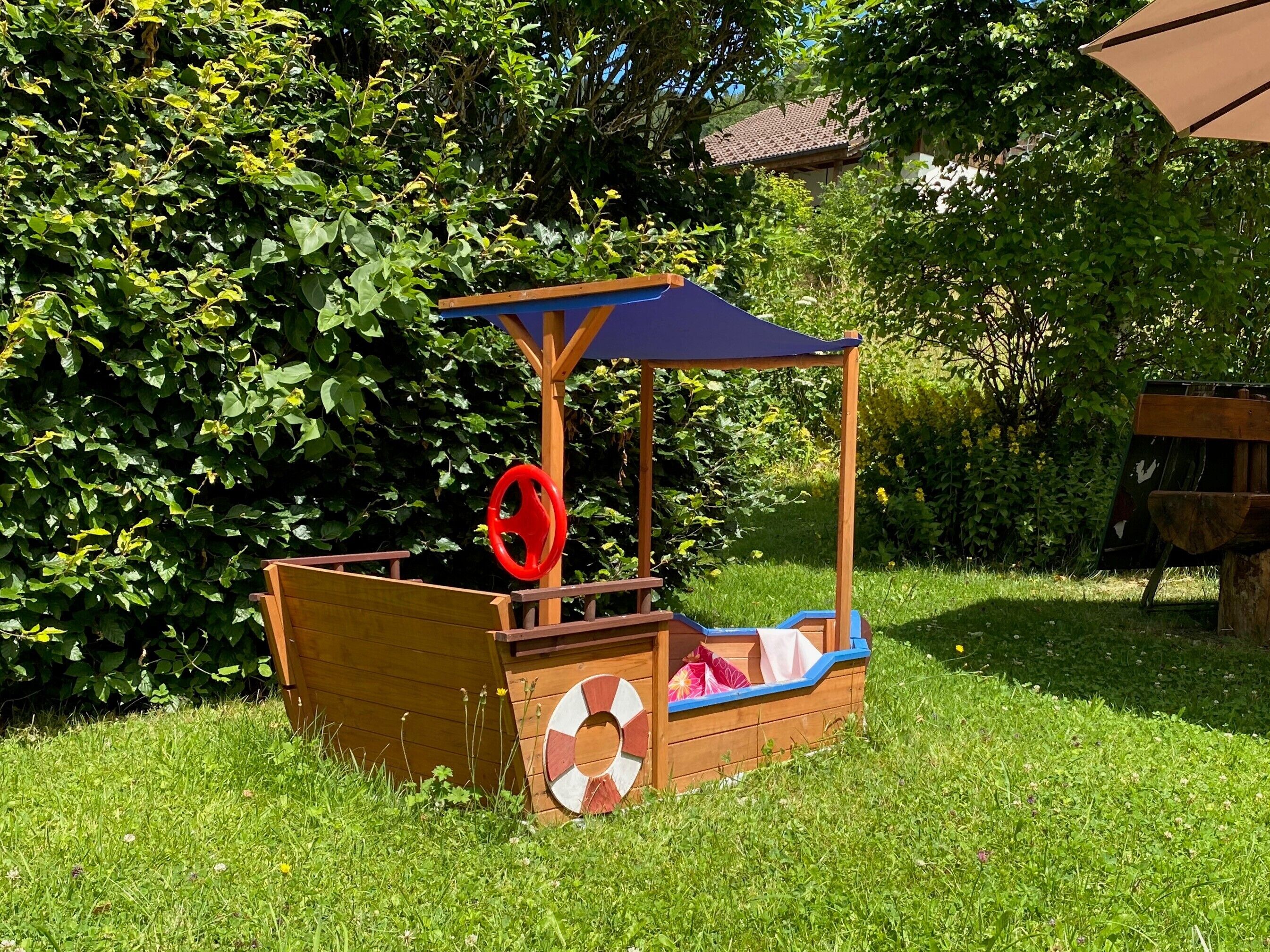 Une cabane en bois pour enfants, avec un toit bleu et un élément décoratif en forme de bouée de sauvetage.