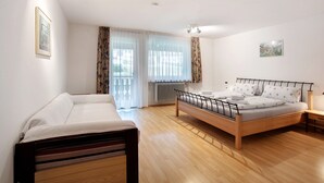A bedroom with a bed, a sofa, a radiator, and a window with curtains. - Apartment 'B, 66 sqm' with Shared Garden, Balcony and Wi-Fi (Sankt Blasien)