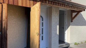 Un edificio residencial con una puerta de garaje de madera, una puerta blanca y un pequeño porche.