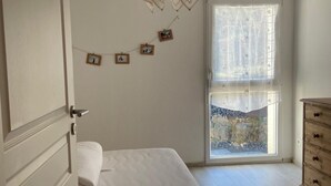 Un dormitorio con una cama, un aparador, una ventana con vistas y una pared con cuadros.