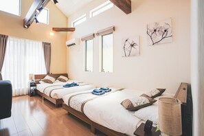 Ein Hotelzimmer mit zwei Betten, einem Schreibtisch und einem großen Fenster mit Vorhängen.