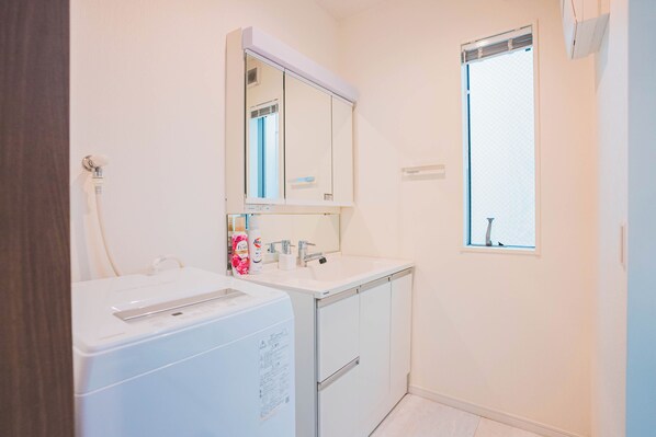 Un baño pequeño y limpio con un lavamanos blanco, un espejo y una ventana.