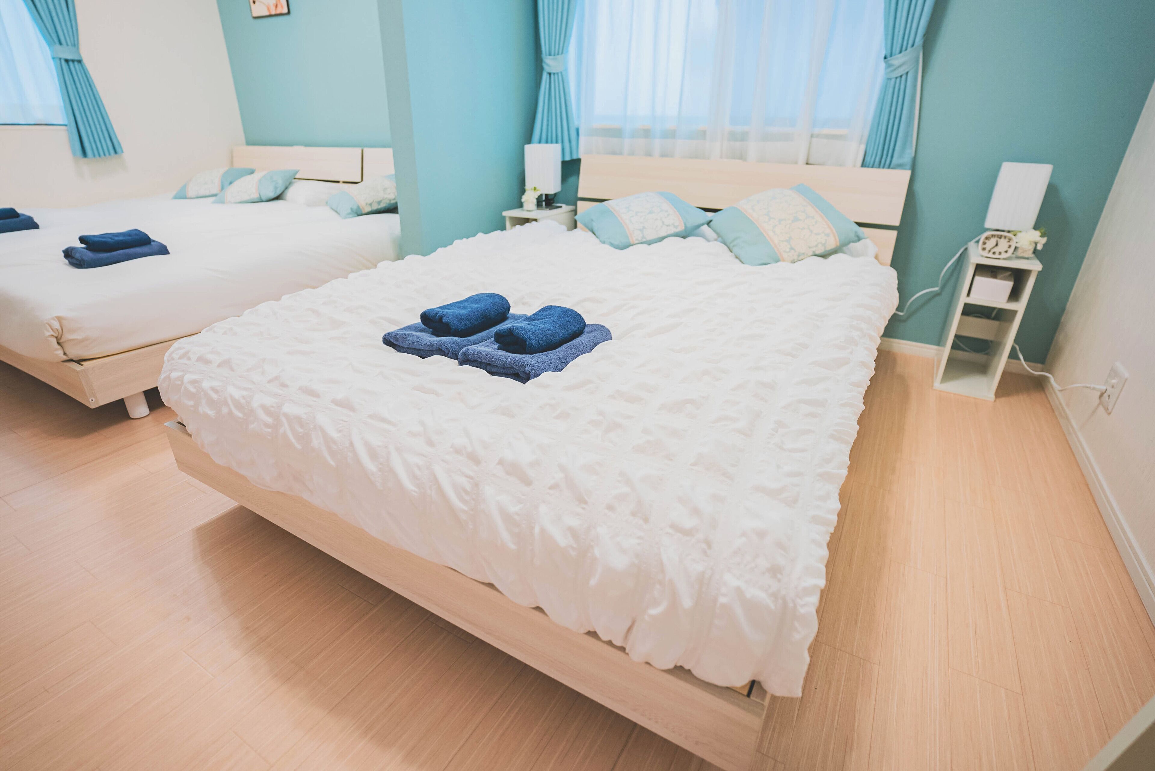 A hotel room with two beds, each with a white duvet and blue towels.