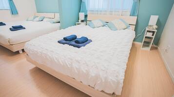 A hotel room with two beds, each with a white duvet and blue towels.
