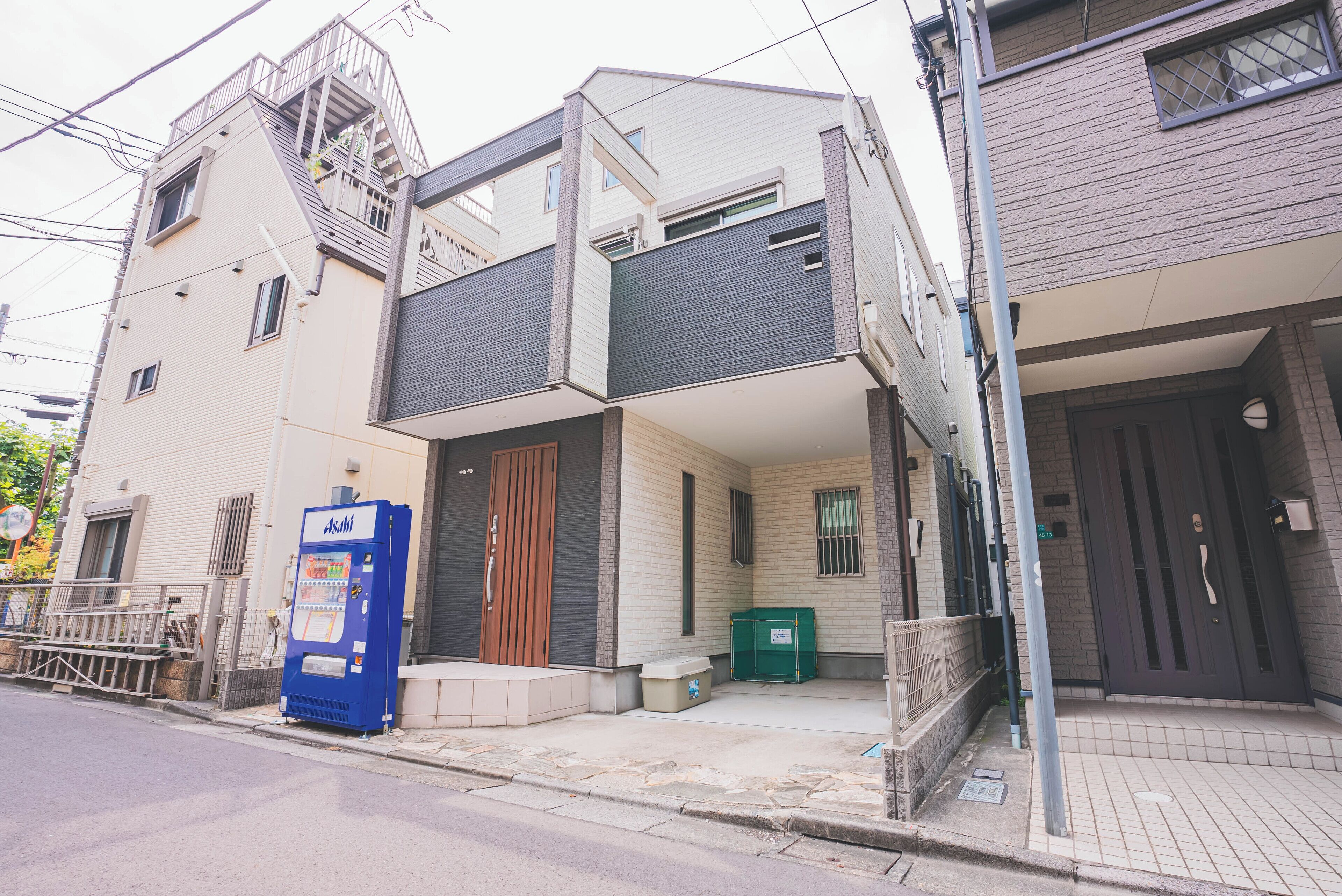 A multi-story building with a ground-level entrance, a vending machine, and a green trash bin outside.