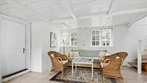 A room with a white door, a sofa, two wicker chairs, a coffee table, and a patterned rug. - Cozy home in Aakirkeby with WiFi (Aakirkeby)