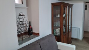 A living room with a grey sofa, a wine rack, and a cabinet with glassware.