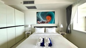 Habitación de hotel con una cama grande, dos mesitas de noche, un cuadro moderno y vistas al exterior.