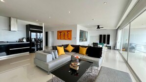 A modern living room with a grey sofa, black coffee table, and yellow cushions. - A26 - 2 Bdr Condo, Stunning Sea View, Karon Beach (Karon)
