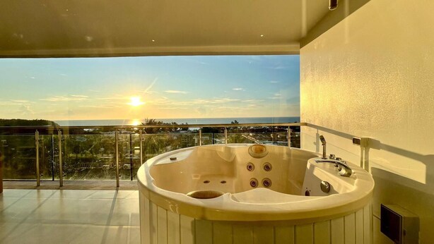 A hot tub on a balcony with a view of the sea and cityscape during sunset. - A26 - 2 Bdr Condo, Stunning Sea View, Karon Beach (Karon)